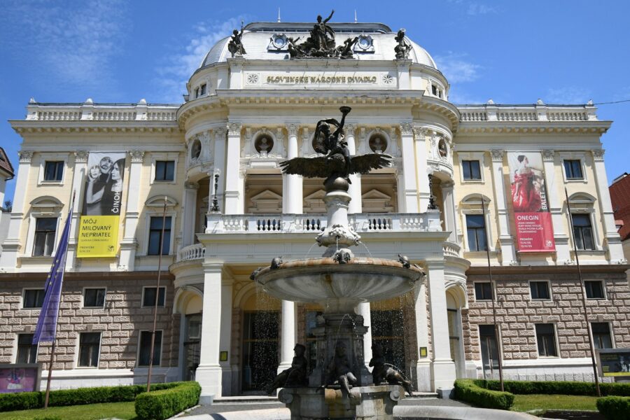 Ornate building with fountain and banners under blue sky